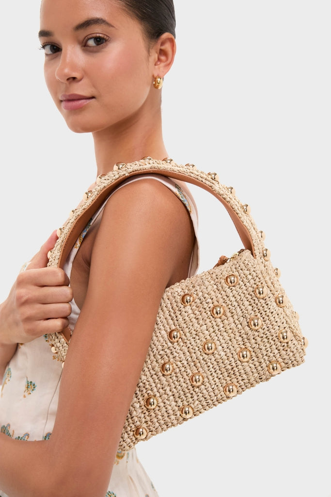 Young woman in a floral dress with an effortless, classic style, holding a straw bag adorned with gold studs, wearing a Pearl Necklace with Carpe Diem Charm.