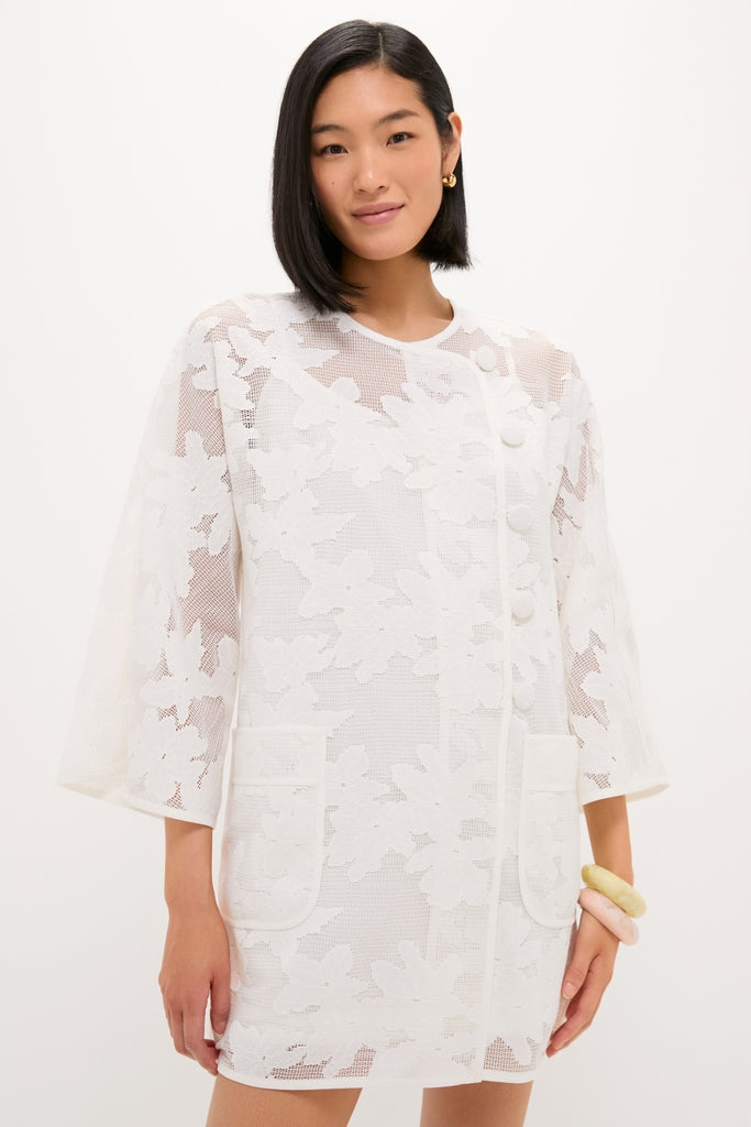 White Floral Lace Sidney Coverup: A classic, semi-sheer knee-length coat with floral lace, three-quarter sleeves, and side buttons, embodying effortless, high-end style with a fun touch.