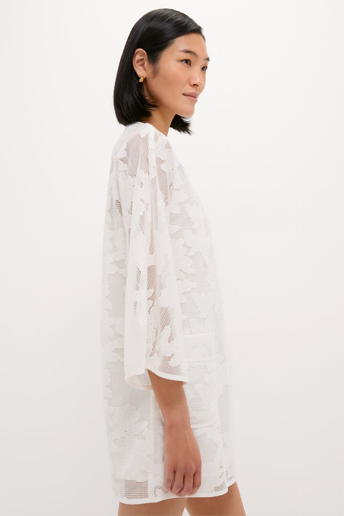 Woman in profile wearing the White Floral Lace Sidney Coverup, a classic and effortless mid-thigh dress with elbow-length sleeves, showcasing fun floral lace for a high-end look.