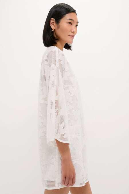 Woman in profile wearing the White Floral Lace Sidney Coverup, a classic and effortless mid-thigh dress with elbow-length sleeves, showcasing fun floral lace for a high-end look.