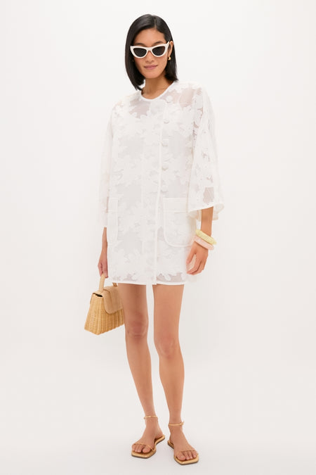 White Floral Lace Sidney Coverup: A classic, effortless mini-dress featuring sheer lace, patch pockets, and elbow-length sleeves, styled with chic accessories for a fun, high-end look.