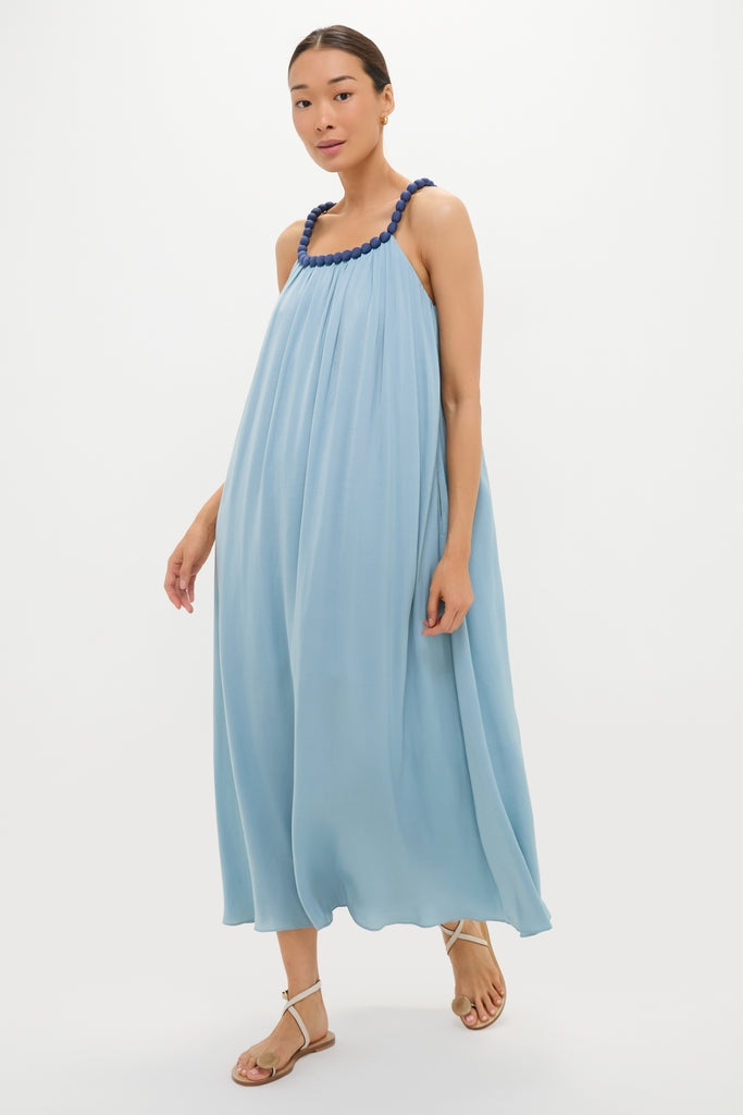 Model wears the Light Blue Chiffon Amelia Bauble Dress, featuring a classic, effortless drapey silhouette, navy beaded straps, and a fun, high-end vibe with flat sandals.