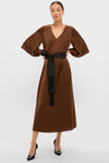 Chocolate Brown Satin Emiliana Maxi Dress with a classic V-neck and wide bell sleeves, featuring an effortless black tassel-tied belt. Paired with high-end pointed-toe heels.