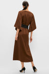 Woman in a classic, effortless Chocolate Brown Satin Emiliana Maxi Dress with kimono sleeves, a tassel-tied belt, and high-end style heels, embodying fun sophistication.