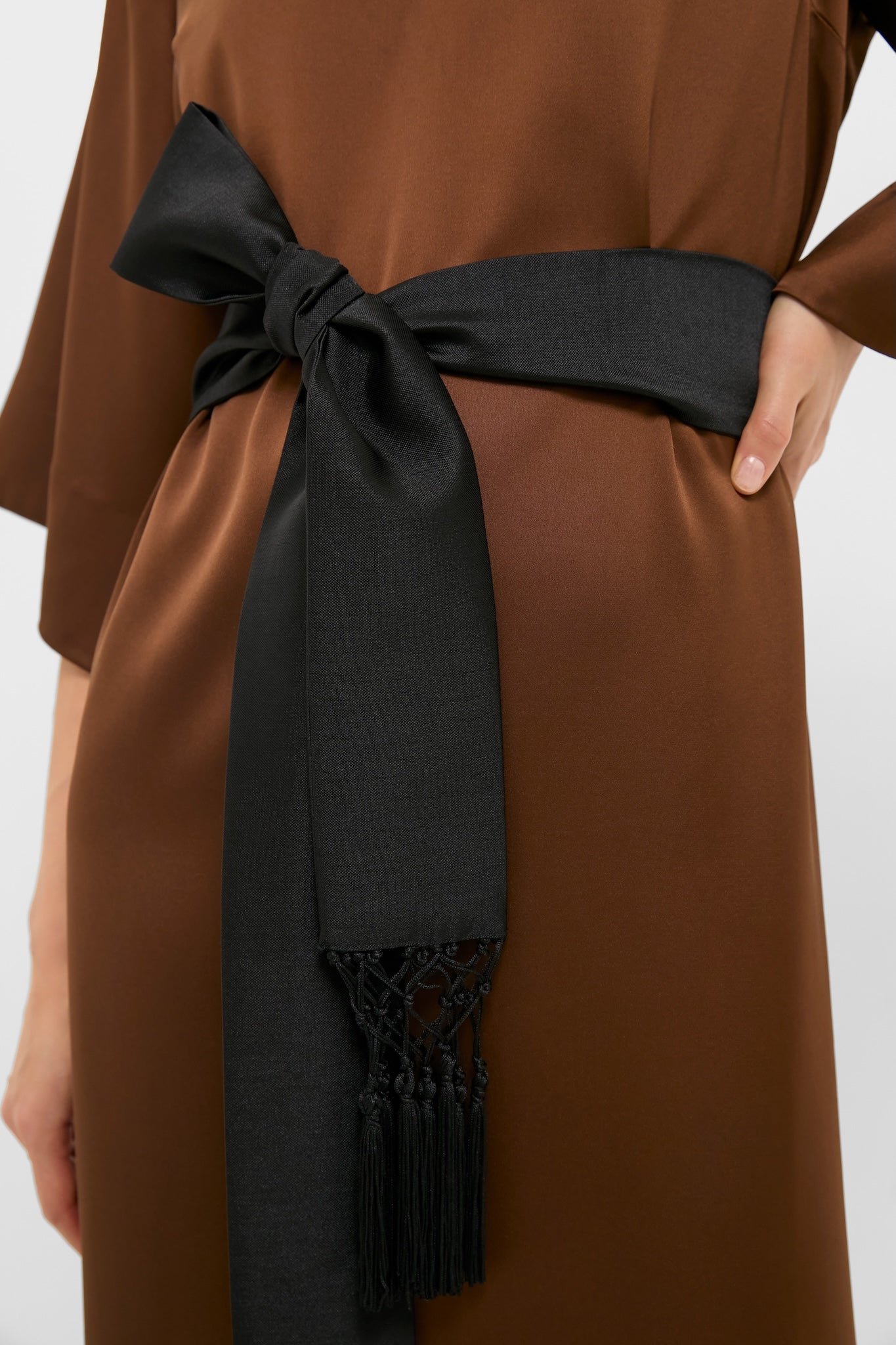 Chocolate Brown Satin Emiliana Maxi Dress features an effortless, classic design with a wide black sash and tassel detail, exuding high-end, fun style for any evening outing.