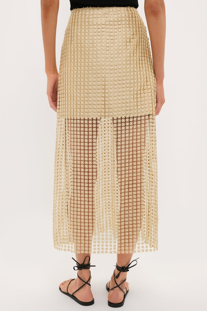 Woman wearing a classic Gold Metallic Star Lace Eve Skirt, sheer below mid-thigh, paired with black sandals. Effortless elegance for a high-end, fun look.