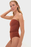 Model wearing the Marsala The Classic One Piece swimsuit, featuring an effortless strapless design, removable braided belt, and gold hoop earrings for a high-end, fun look.