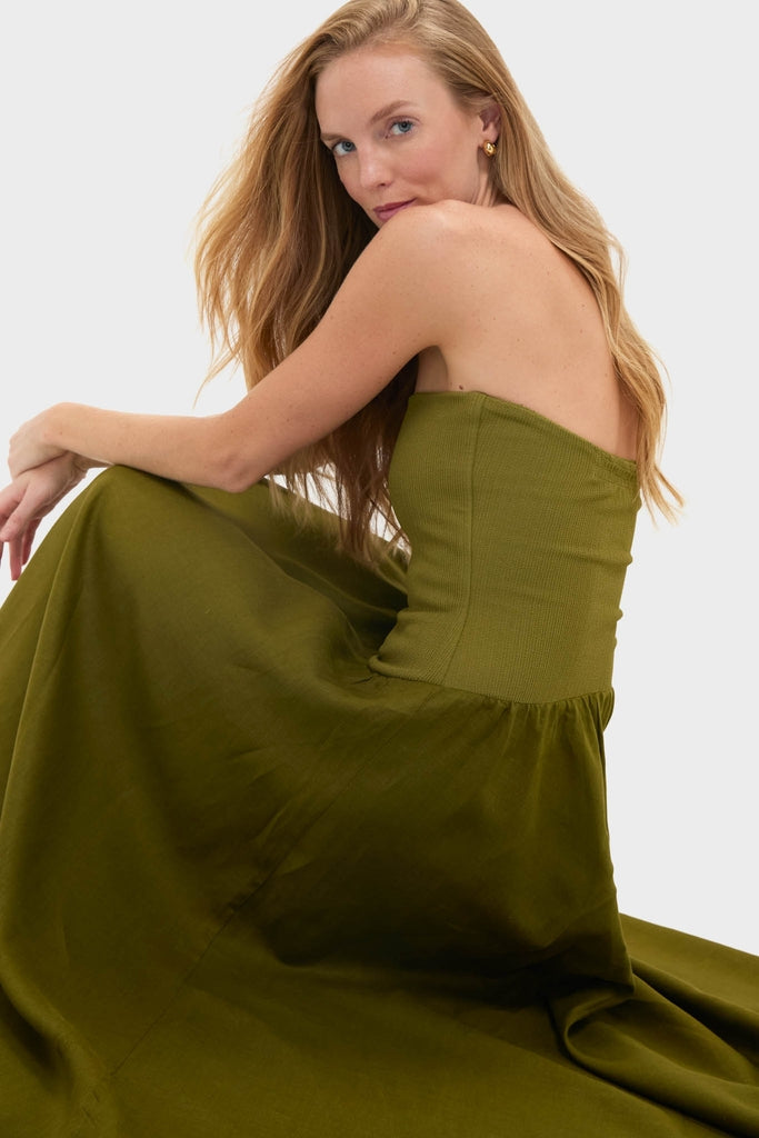 Woman in a classic, olive-green, strapless Green Empowerment Movement Ankle Skirt, showcasing its versatile, high-end design as both a dress and skirt.