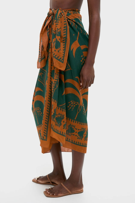 Rust and Dark Green Dance of Pareo: A classic, effortless wrap skirt with tropical print, tied at the waist, paired with fun, high-end flat sandals.