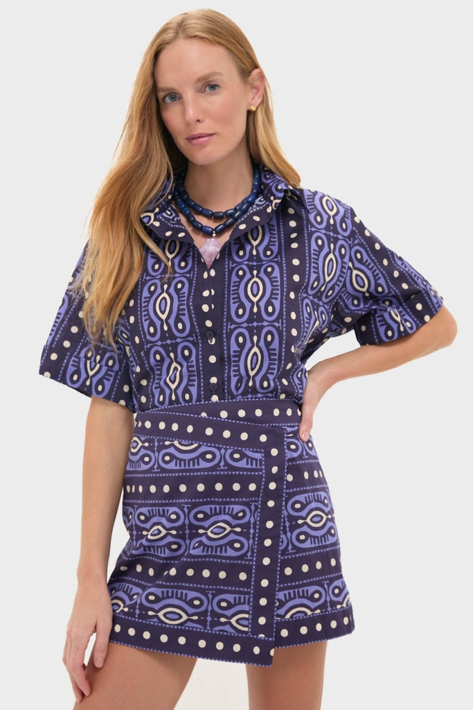 Model wearing the Navy and Ecru Salty Promises Shirt, a classic poplin top with a geometric print. Effortlessly paired with a matching high-waisted mini skirt and chunky bead necklaces.