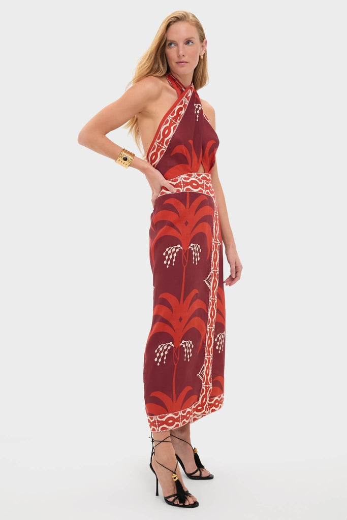 Model wearing the Wine and Red Buen Viento Ankle Dress, a classic and effortless halter-neck maxi with palm motifs, paired with high-end tassel sandals and a gold cuff.