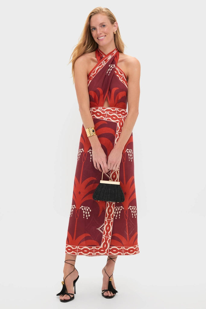 Model wearing the classic Wine and Red Buen Viento Ankle Dress with a bold botanical print, styled with an effortless black wicker handbag and high-end tassel sandals.