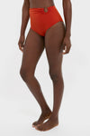 Person wearing classic, high-end Fire Red Taita Bikini Bottoms with a high-rise silhouette and bead accent, embodying an effortless, fun style against a plain white background.