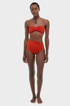 Woman models Fire Red Taita Bikini Bottom, featuring a classic high-rise silhouette with ruching and bead accent, paired with a twist-front bandeau top for an effortless, high-end look.