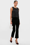Woman models the classic Black Taffeta Keating Top, a sleeveless, high-end satin blouse, paired with elegant accessories and slim-leg pants for an effortless, fun look.