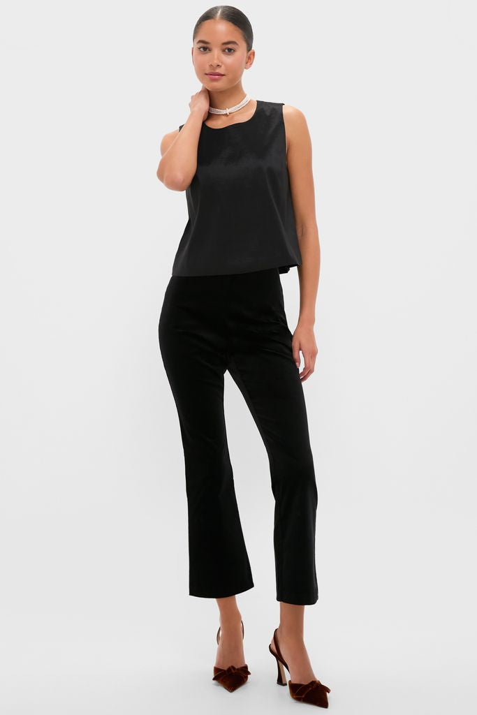 Young woman models the Black Taffeta Keating Top, a classic, sleeveless satin blouse with a relaxed fit, exuding effortless, high-end style paired with fitted black pants.