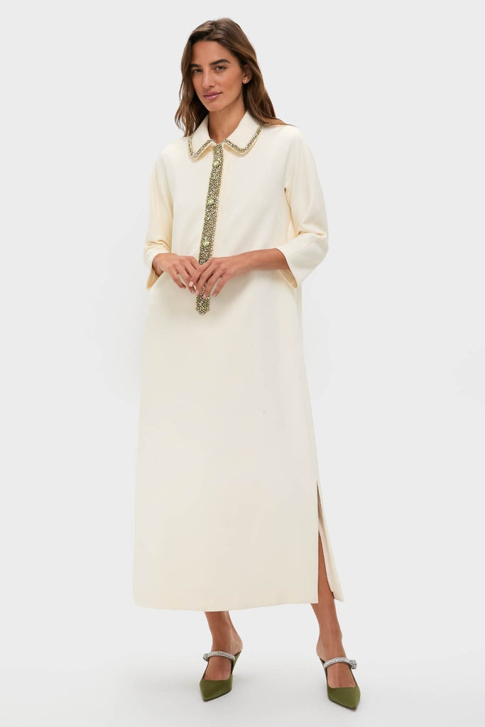 Winter White Embellished Nicola Maxi Dress exudes effortless elegance with classic three-quarter sleeves, gold-tone embellishments, and a fun side slit, paired with high-end olive-green jeweled heels.