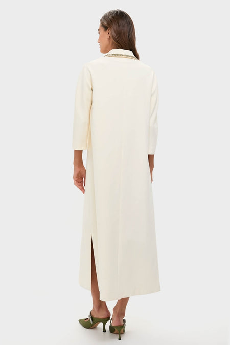 Woman modeling the Winter White Embellished Nicola Maxi Dress with a classic collar, metallic trim, and three-quarter sleeves, paired with effortless olive-green heeled mules.