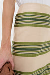 Close-up of a classic, high-waisted Satin Stripe Ellington Skirt in beige with dark-green stripes, paired with a white top, embodying effortless, high-end style.