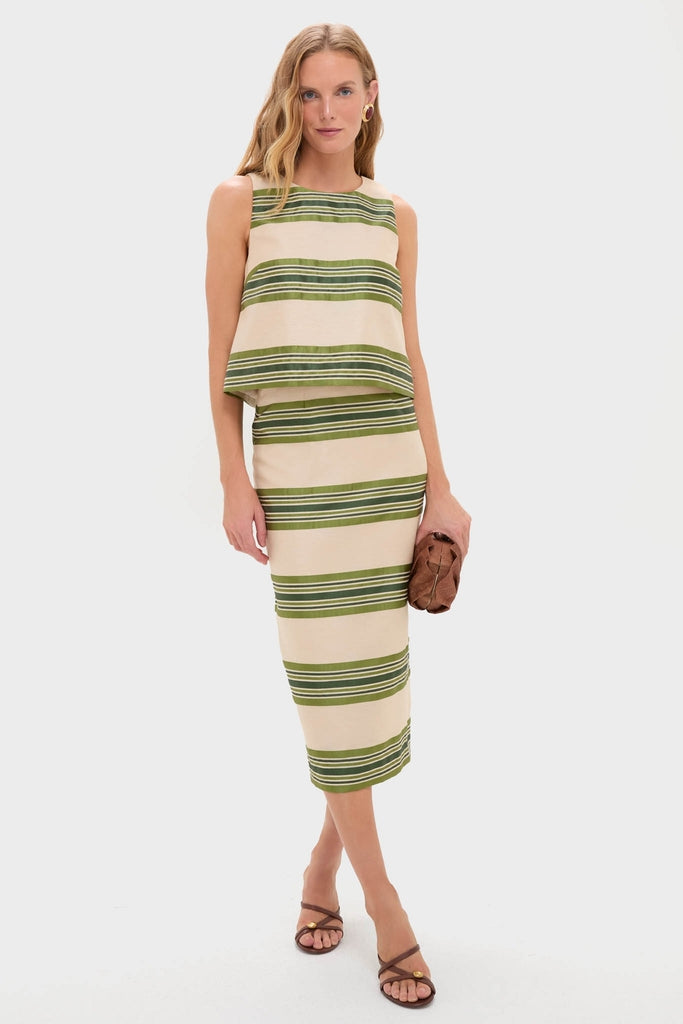 Model in a classic, effortless Satin Stripe Ellington Skirt set, holding a woven clutch, embodying fun, high-end style with minimal gold hoop earrings and strappy sandals.