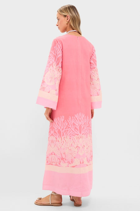 Woman in Hopewell Coral Printed V-Neck Lorena Caftan with coral-reef motif, embodying effortless, high-end style. Classic, fun look with bell sleeves and strappy sandals.