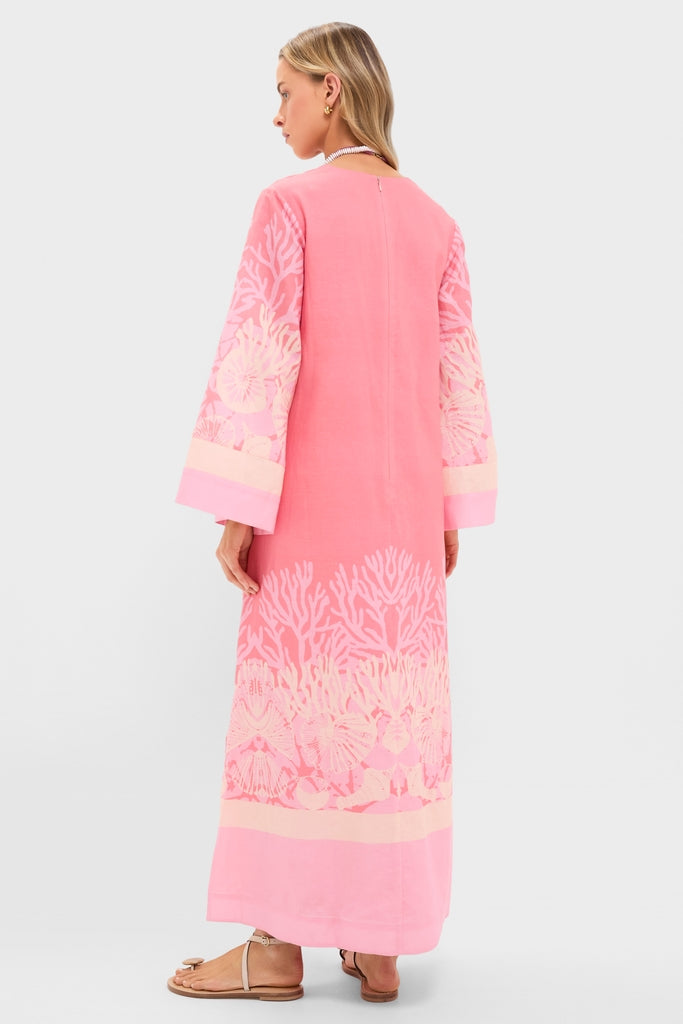 Woman in Hopewell Coral Printed V-Neck Lorena Caftan with coral-reef motif, embodying effortless, high-end style. Classic, fun look with bell sleeves and strappy sandals.