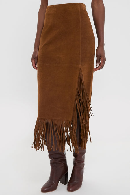 Clove Calf Roughout Suede Midi Skirt with side slit and fringe detailing, paired with knee-high leather boots, embodies a classic, effortless, and high-end style.