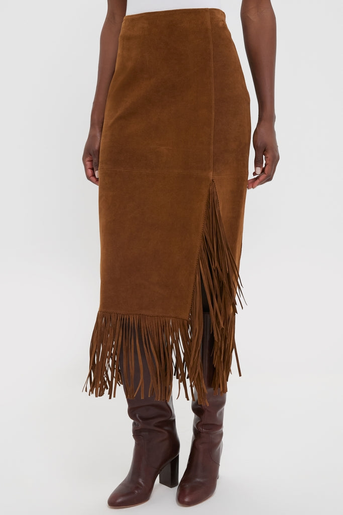 Clove Calf Roughout Suede Midi Skirt with side slit and fringe detailing, paired with knee-high leather boots, embodies a classic, effortless, and high-end style.