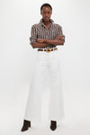 Person wearing Nevis Cotton Twill Woven Standard Flare Pants, styled effortlessly with a classic striped shirt and boots, showcasing a fun, high-end, tailored look.