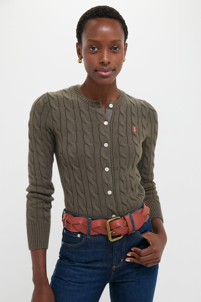 Young woman in a classic, fitted Harvest Olive Cardigan with cable-knit detailing, paired effortlessly with high-waisted jeans and a braided leather belt for a high-end, fun look.