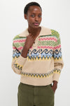 Young person in a classic, high-end Tan Multi Cotton Wool Blend Long Sleeve Tie Pullover with vibrant Fair Isle patterns, embodying effortless style and fun, paired with olive-green pants.