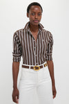 Woman wearing classic Dark Brown and White Stripe Long Sleeve Button Down, effortlessly styled with high-waisted pants and a belt, embodying Tuckernuck's fun, high-end fashion ethos.