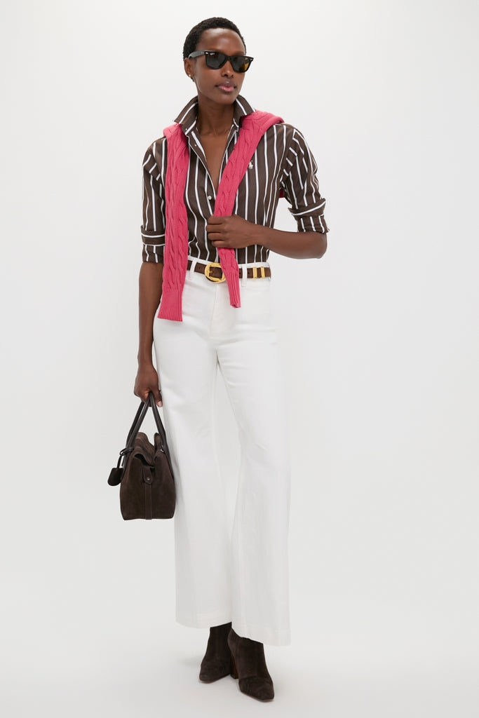 Person wearing the Dark Brown and White Stripe Long Sleeve Button Down with rolled sleeves, styled with a pink sweater, white trousers, and a suede handbag for an effortless, high-end look.