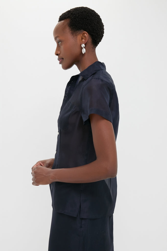 Atlantic Silk Organza Woven Short Sleeve Button Down on a woman, showcasing its classic, tailored silhouette, shell buttons, and waist darts for an effortlessly cool, high-end look.