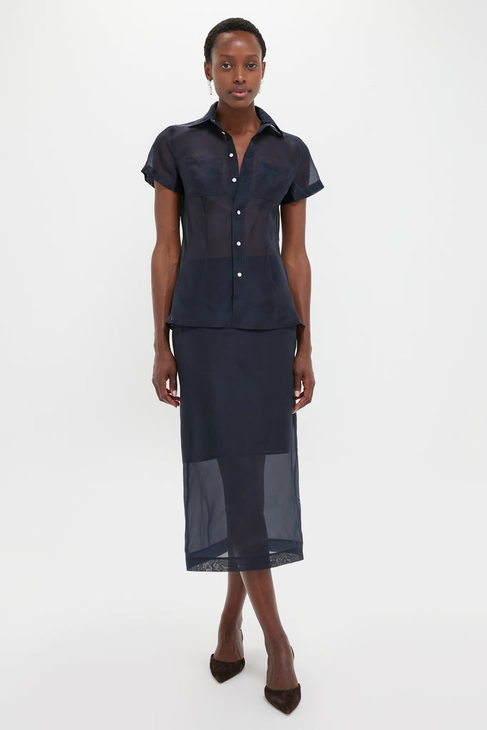 Woman models Atlantic Silk Organza Woven Short Sleeve Button Down, showcasing a classic, effortless look with sheer silk fabric and tailored details, embodying high-end, fun style.