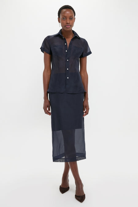 Woman models Atlantic Silk Organza Woven Short Sleeve Button Down, showcasing a classic, effortless look with sheer silk fabric and tailored details, embodying high-end, fun style.