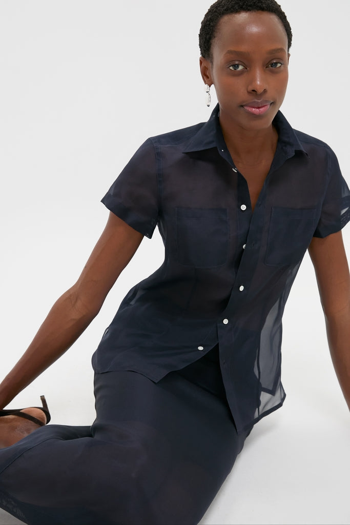 Model wearing Atlantic Silk Organza Woven Short Sleeve Button Down, showcasing classic, effortless style. Features sheer silk, tailored silhouette, shell buttons, exuding fun, high-end elegance.