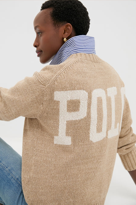 Person wearing a Tan Heather Cotton Long Sleeve Crewneck by Polo Ralph Lauren with POLO on back, styled over a striped shirt and jeans for an effortless, classic look.