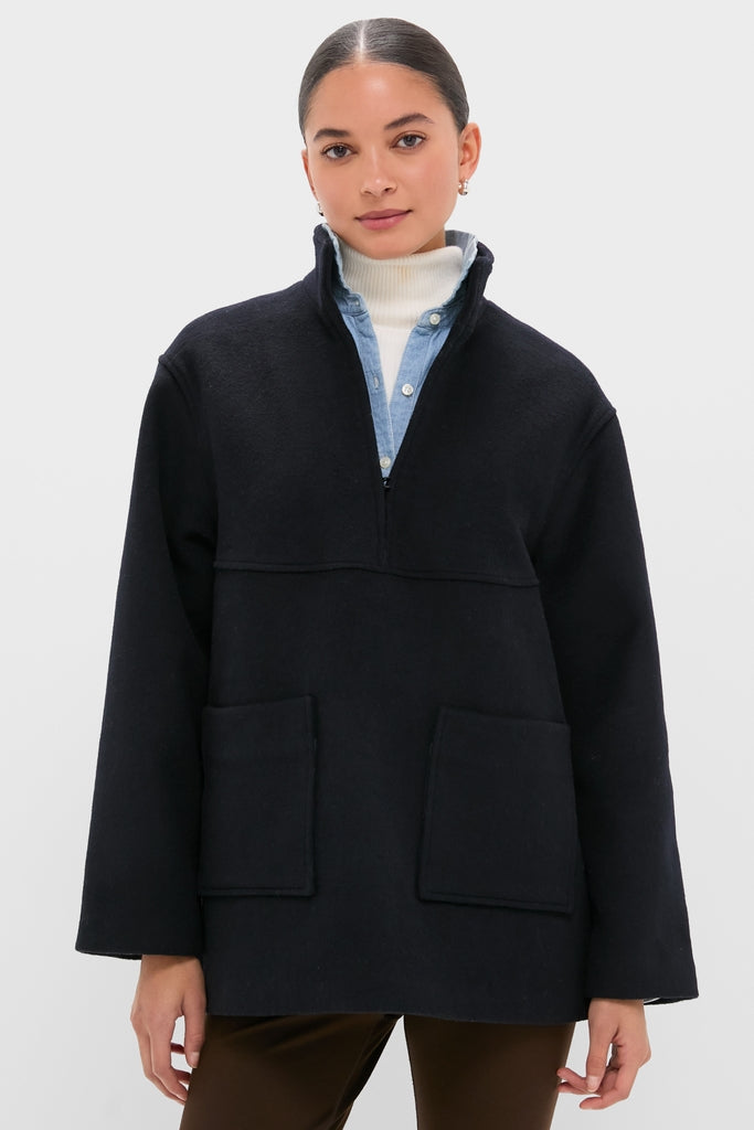 Model wearing a classic, high-end Navy Wool Joan Coat with a high stand-up collar and patch pockets, layered over a denim shirt and white turtleneck for an effortless, fun style.