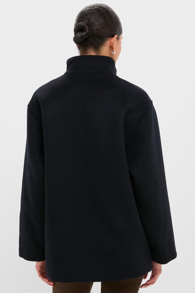 Person wearing the Navy Wool Joan Coat, showcasing its classic high-neck, long-sleeved design, embodying an effortless, high-end style against a light background.