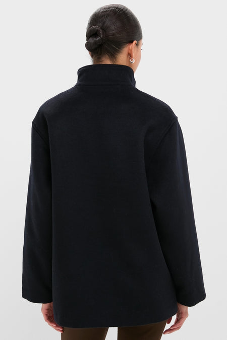Person wearing the Navy Wool Joan Coat, showcasing its classic high-neck, long-sleeved design, embodying an effortless, high-end style against a light background.
