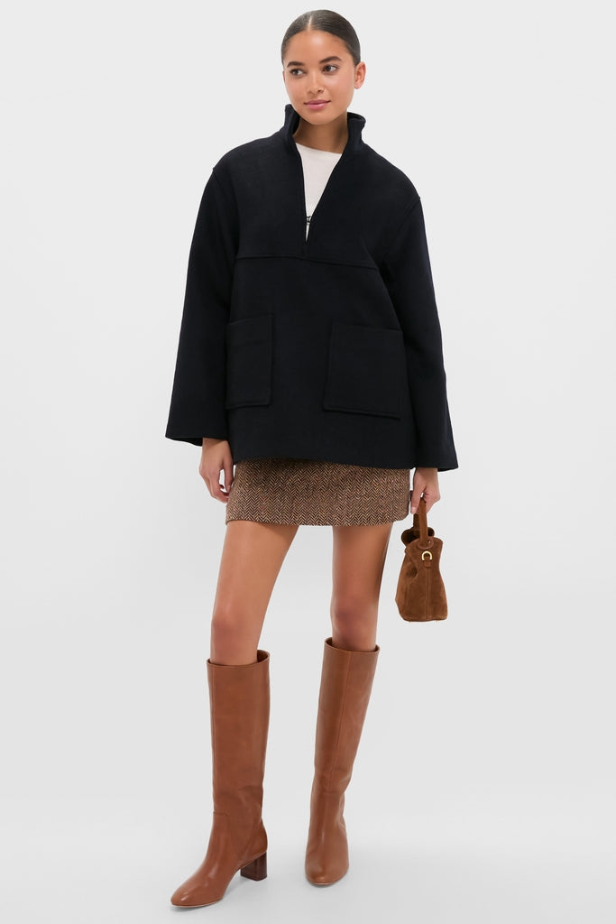 Young woman models the classic Navy Wool Joan Coat with a chic boxy fit and oversized pockets, styled effortlessly with a mini skirt and boots for a high-end look.