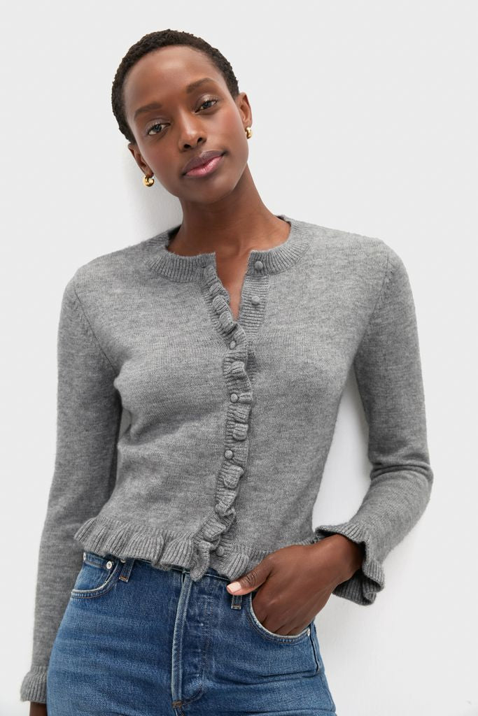 Woman in a Grey Knit Patterson Ruffle Sweater, showcasing classic ruffle trims on placket and cuffs, paired effortlessly with jeans for a fun, high-end look.