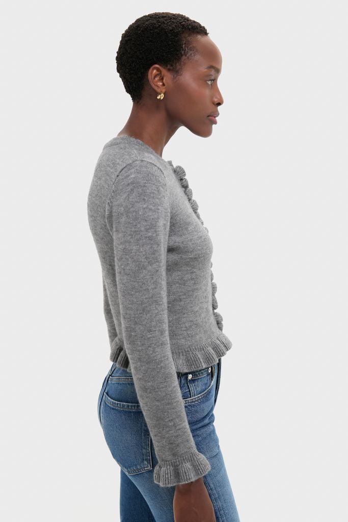 Woman in profile wearing the classic Grey Knit Patterson Ruffle Sweater with decorative bobble detailing, paired effortlessly with jeans for a fun, high-end look.