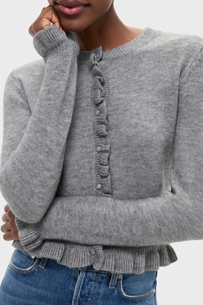 Effortlessly chic, the Grey Knit Patterson Ruffle Sweater features a classic design with ruffle details and covered buttons, styled with jeans for a high-end, fun look.