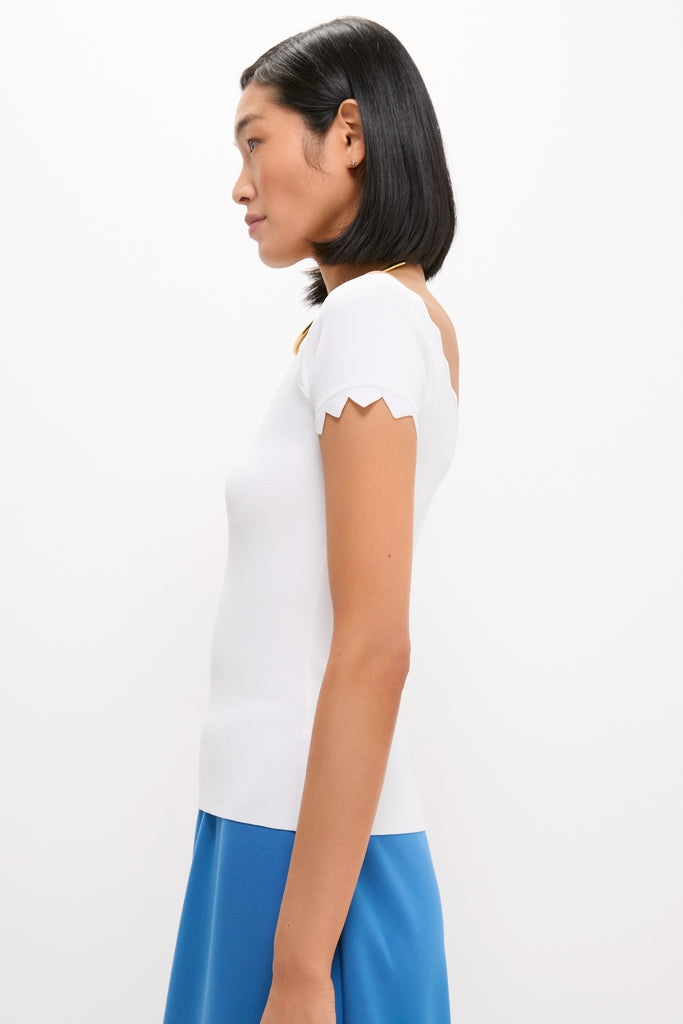 Young woman in a classic, effortless White Off-the-Shoulder Ric Rac Compression Elliston Shirt, showcasing high-end style with fun, scalloped sleeves and a sleek, modern look.