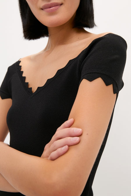 Person wears the Black Off-the-Shoulder Ric Rac Compression Elliston Shirt featuring classic ric-rac trim and a flattering fit, embodying an effortless, high-end style.