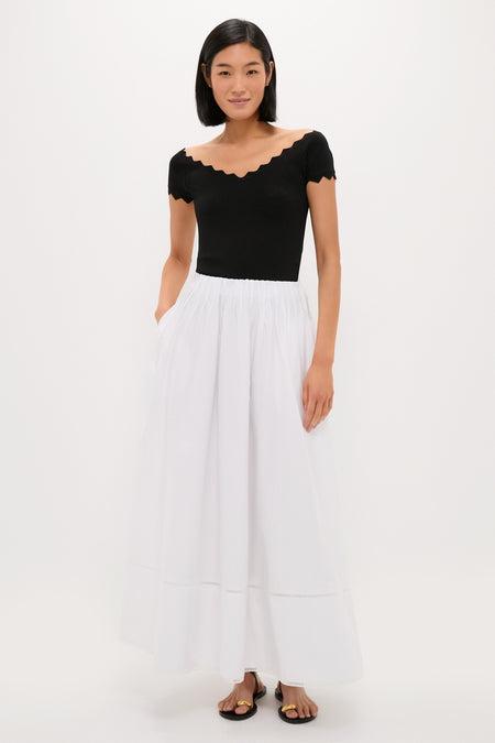 Black Off-the-Shoulder Ric Rac Compression Elliston Shirt, classic and chic with ric-rac trim, styled effortlessly with a full white skirt, embodying high-end elegance.