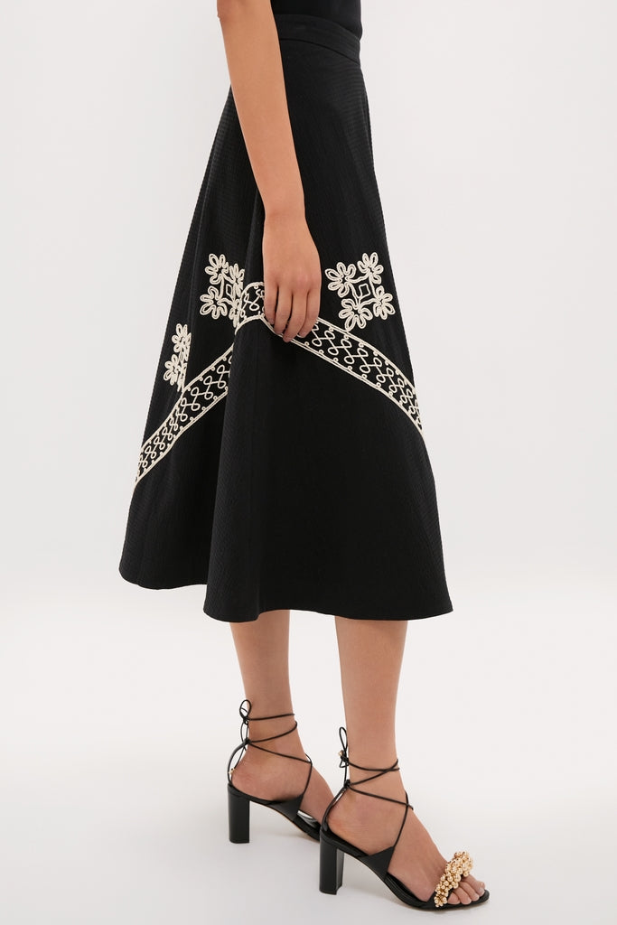 Wearing the classic Soutache Cotton Andrea Circle Skirt, paired with effortless block-heeled sandals, showcasing fun, high-end style with intricate floral and chain-link embroidery.