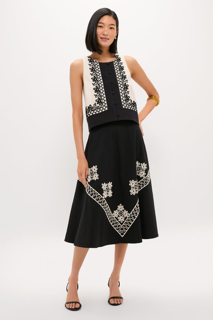 Woman in a classic, coordinated two-piece featuring the high-end Soutache Cotton Andrea Circle Skirt and a sleeveless knit vest, exuding effortless style with fun, embroidered patterns.